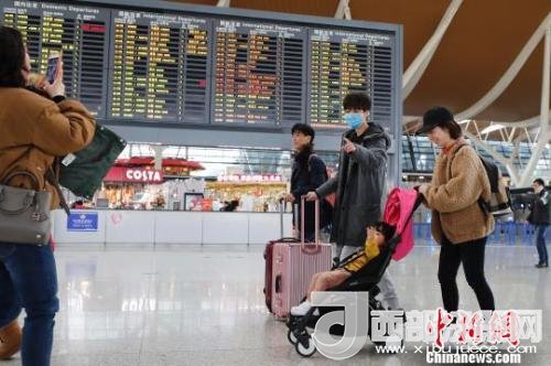 旅客帶著孩子前往辦票柜臺辦理登機手續(xù)?！∫罅⑶?攝