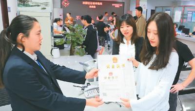 河北省承德市網(wǎng)絡(luò)代購經(jīng)營者陳晨(右)從工作人員手中接過帶有統(tǒng)一社會(huì)信用代碼的營業(yè)執(zhí)照。 劉環(huán)宇攝(人民圖片)