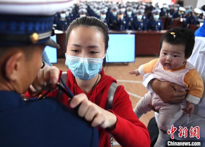 新消防員楊振的妻子彭莉與女兒現(xiàn)場見證丈夫加入“火焰藍(lán)”的神圣時刻?！⒅铱?攝